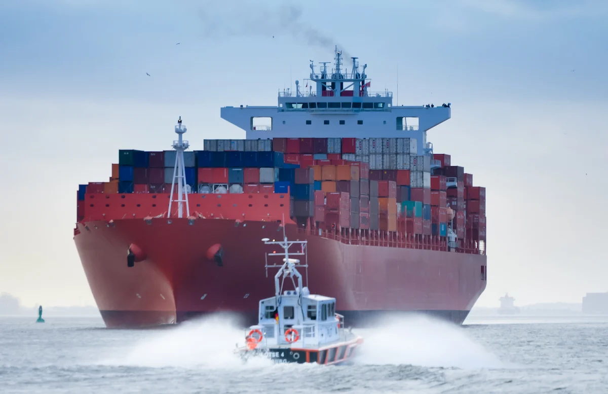 Image of a tugboat next to a cargo ship in the ocean